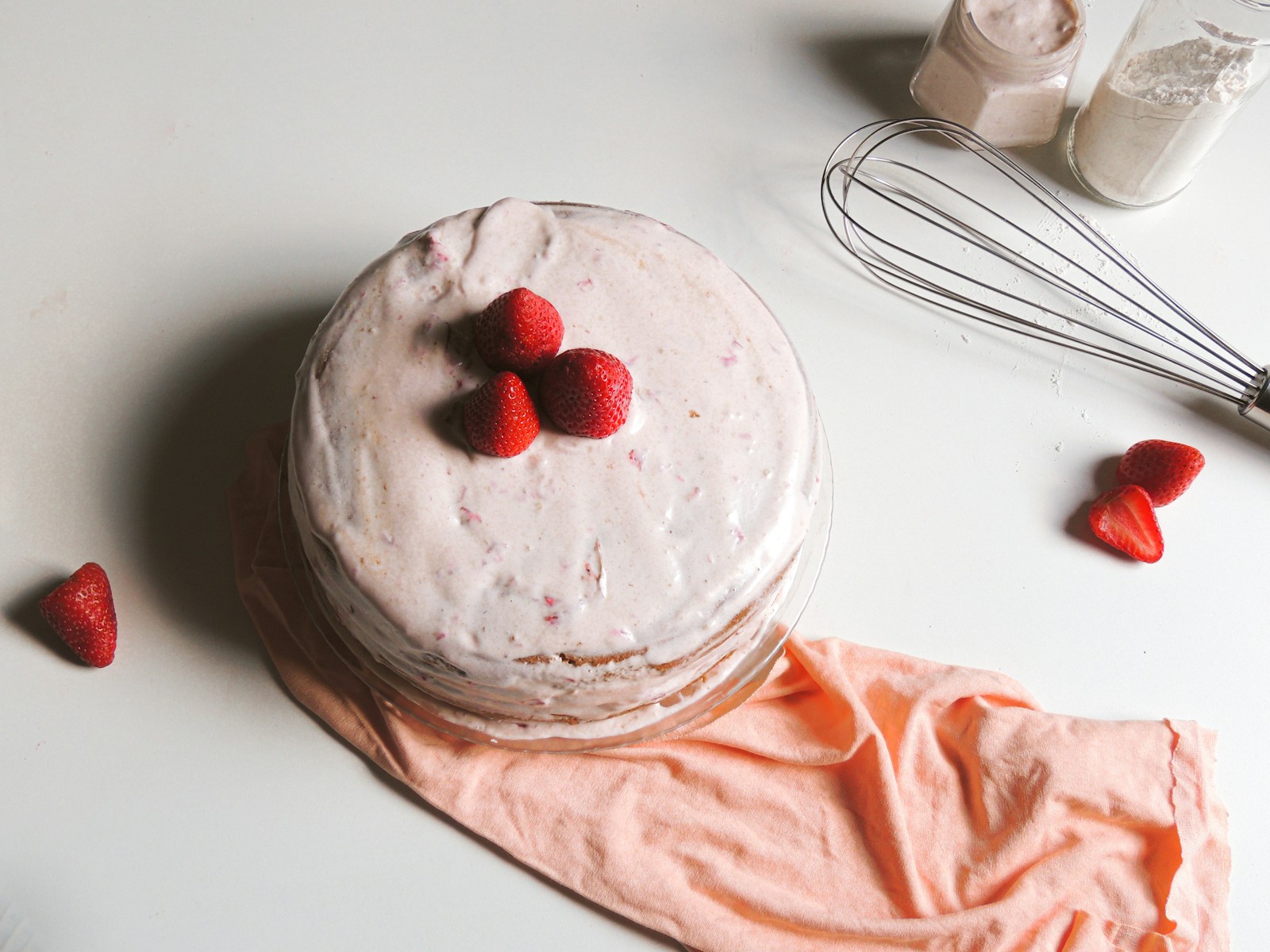 a cake sitting on top of a table next to a whisk